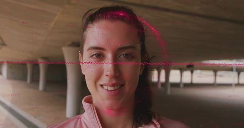 Smiling woman in pink zip-up jacket with red glitch effect in underpass
