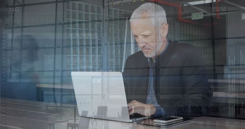Senior Businessman Using Laptop in Modern Office Environment