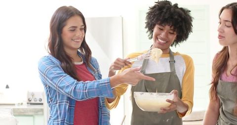 Diverse Female Friends Joyfully Mixing Batter in Modern Kitchen
