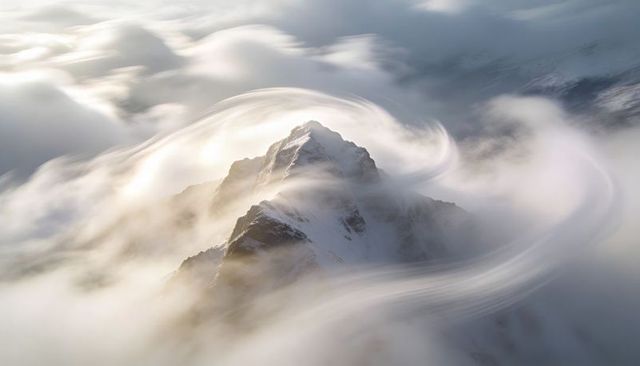 Snow-Dusted Peak Piercing Alpine Cloud Sea with Swirling Lenticular Light Trails at Sunrise