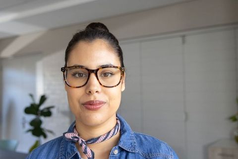 Confident woman wearing tortoiseshell glasses and denim shirt with neck scarf