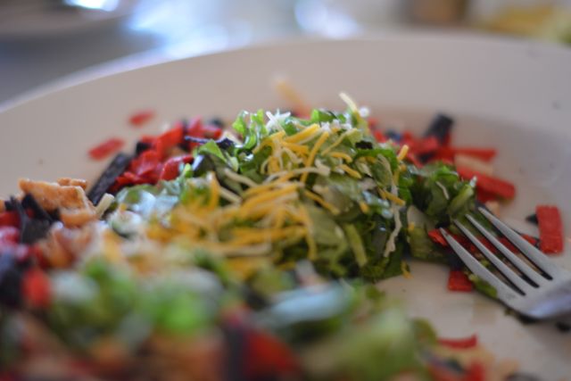 Healthy and colorful mixed salad displayed up close, topped with shredded cheese and red onion. Perfect for themes related to nutrition, healthy lifestyles, vegetarian meals, and food preparation. Ideal for illustrating content for food blogs, restaurant menus, and dietary guides.