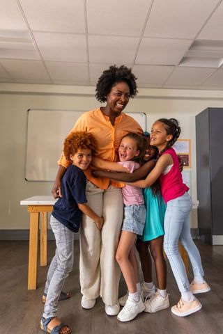 African American Teacher Hugging Smiling Elementary Students Joyful Classroom Bonding