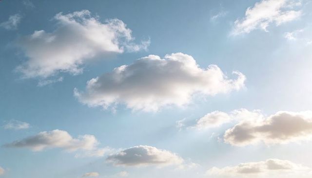 Sunlit Cumulus Clouds Drifting Across Pale Blue Sky with Soft Sun Glare, Airy Background
