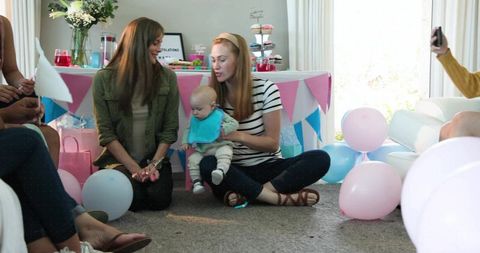 Mother holding baby at colorful baby shower with balloons, bunting and cupcakes