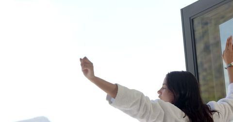 Teenage Girl Embracing Morning Sunshine on Balcony