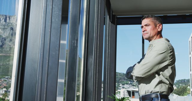 Man Standing Near Window Gazing Outside in Modern Apartment - Download Free Stock Images Pikwizard.com