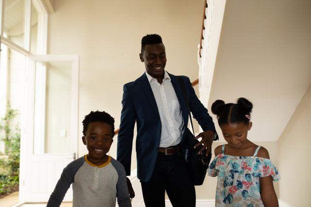 African American man enjoying his time at home with his daughter and son, coming back from work smiling. Family togetherness domestic life.