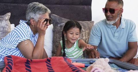 Family bonding time with grandparents and child around luggage