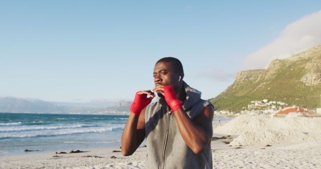 Focused african american man boxing, exercising outdoors by the sea. fitness, healthy and active lifestyle concept.