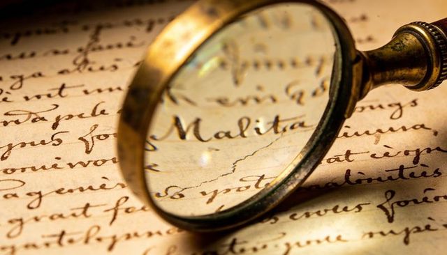 Antique brass magnifying glass enlarging cursive manuscript on sepia parchment