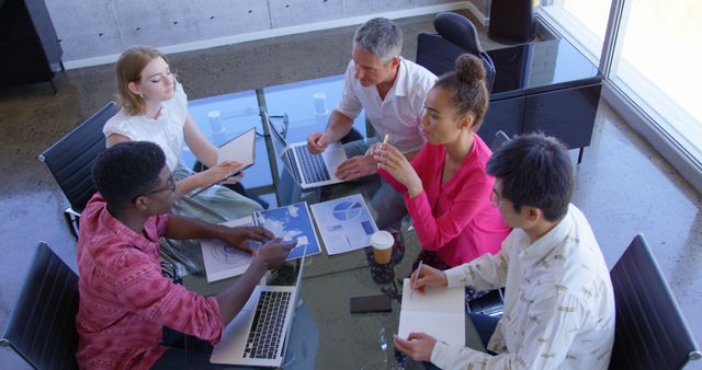 Multi-ethnic colleagues analyze graphs during a high-angle office meeting in 4K. - Download Free Stock Photos Pikwizard.com