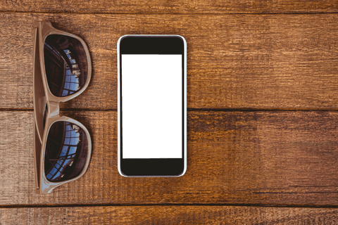 Transparent sunglasses and smartphone on wooden surface