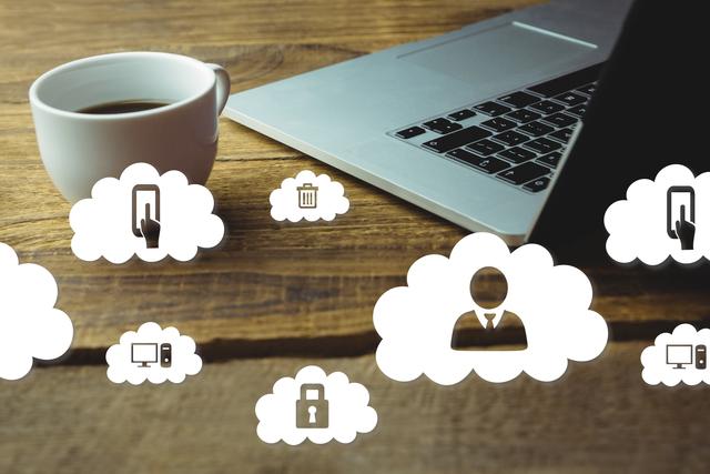 Image depicts a workspace with a laptop and a cup of coffee on a wooden desk, overlain with cloud computing icons representing data storage and security. Ideal for articles and presentations on technology, cloud storage, data security, and remote work setups. Useful for business-related materials, IT services, and software development content.
