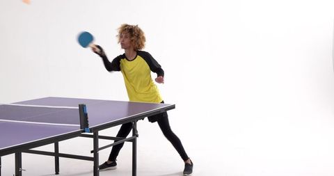 African American Woman Energetically Playing Table Tennis in Studio