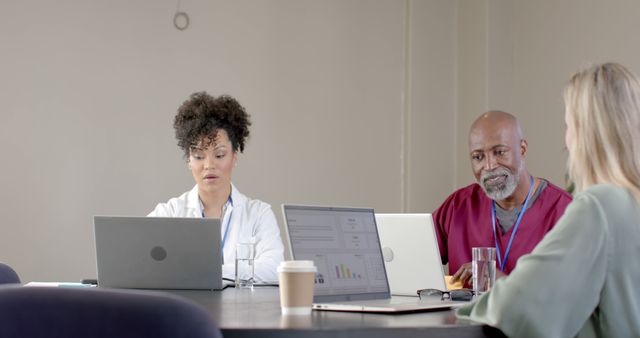 Diverse professionals working on laptops during a meeting in modern office - Download Free Stock Images Pikwizard.com