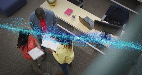 Team reviewing documents in open-plan office with blue data overlay for collaboration