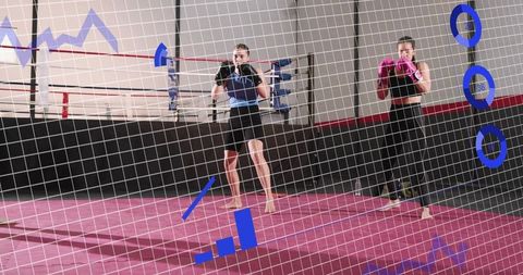Two women sparring in boxing ring wearing blue waist protector and pink gloves, fitness