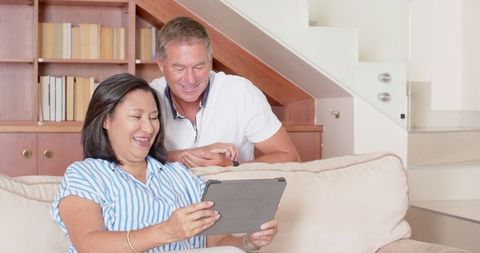 Happy Couple Relaxing in Living Room with Tablet