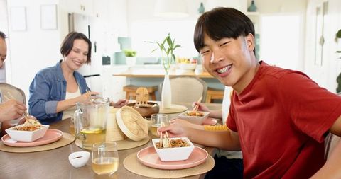 Family Enjoying Traditional Meal with Chopsticks in Modern Home Kitchen