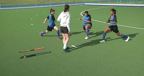 Female coach leading team warm-up on hockey field