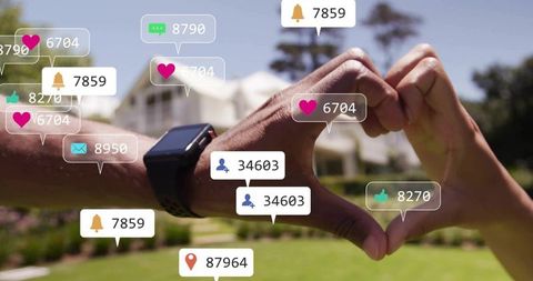 Couple forming heart with hands showing smartwatch and social media alerts in sunny suburban yard
