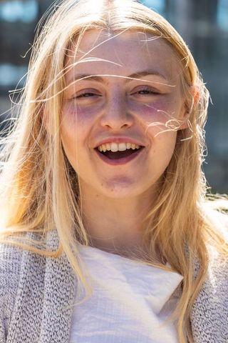 Sunlit young woman laughing and squinting outdoors close-up portrait