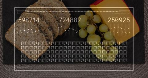 Seeded bread and green grape grazing board with red-rind cheese on slate flatlay hud