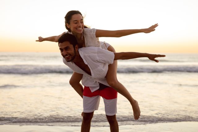 Young man giving piggyback ride to woman on the beach