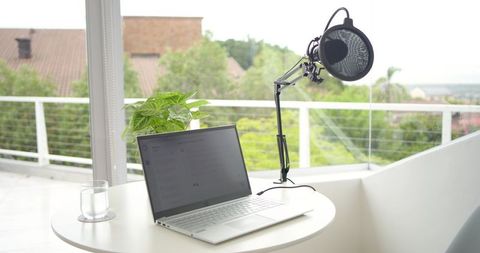 Minimalist balcony workspace with laptop, task lamp, indoor plant, bright natural light