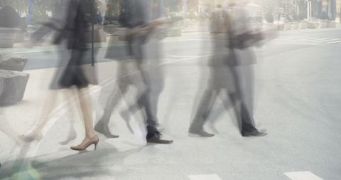 Blurred business commuters walking briskly across city crosswalk conveying urban hustle