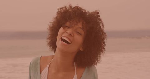 Carefree Woman Laughing by Ocean on Sunny Day