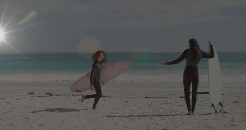Excited female surfer running towards fellow surfer on beach