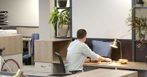 Man Working in Modern Open-Plan Office with Greenery and Snacks