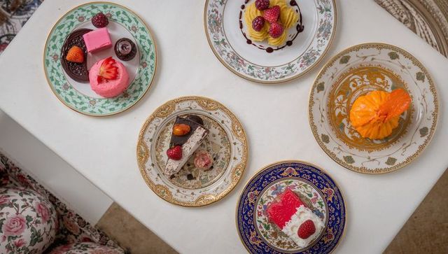 Displaying assorted pastries on ornate porcelain plates over white tabletop, pastel desserts