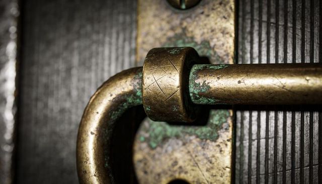 Aged brass sliding bolt latch showing verdigris, heavy patina, scratches and antique d-ring