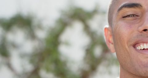 Half face of smiling man with blurred nature background