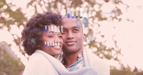 Smiling couple leaning close wrapped in blanket in park with warm bokeh and glitch overlay