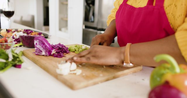 Person chopping vegetables on a cutting board in a modern kitchen. Images like this are perfect for cooking blogs, healthy eating promotions, culinary magazines, and kitchen appliance advertisements. Use this vibrant image to depict the concept of fresh, homemade meals, nutrition, and culinary creativity.