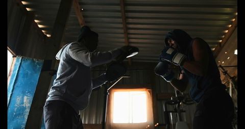 Boxer and Trainer Practicing Boxing Techniques in Dimly Lit Gym