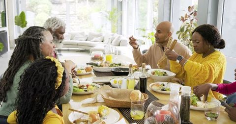 Multigenerational family sharing sunlit healthy meal around modern open-plan dining table