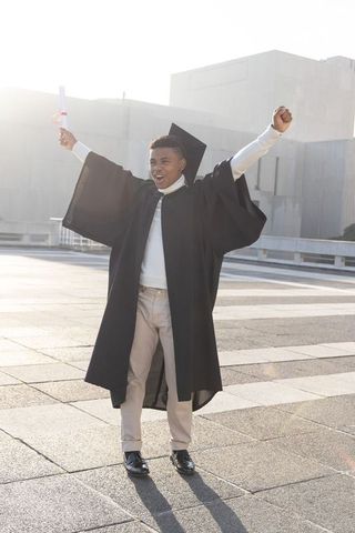 Triumphant african american graduate celebrating with diploma on urban rooftop plaza