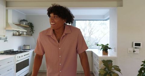 Cheerful Man in Stylish Kitchen Admires Stainless Steel Stove