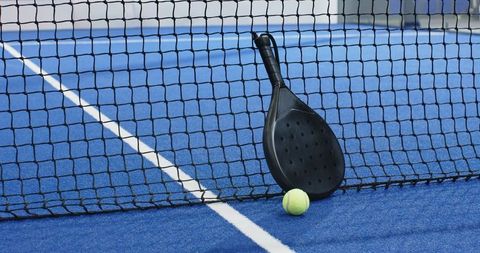 Black Padel Racket with Ball on Blue Turf Court