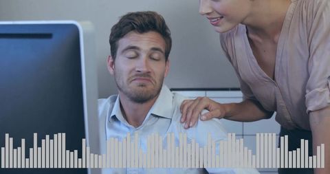 Coworkers reacting to computer alert woman comforting grimacing man at desk