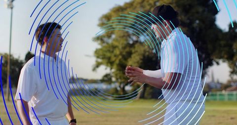 Coaching conversation on waterfront field with athletes gesturing and blue circular overlay