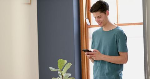 Happy Young Man Connecting with Smartphone Indoors