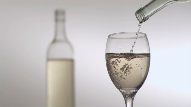 Captures wine being poured into a glass showcasing artful bubbles. Useful for advertisements, bar menu designs, or wine product promotions.