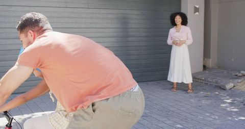Father Teaching Daughter to Ride Bike as Mother Watches and Smiles