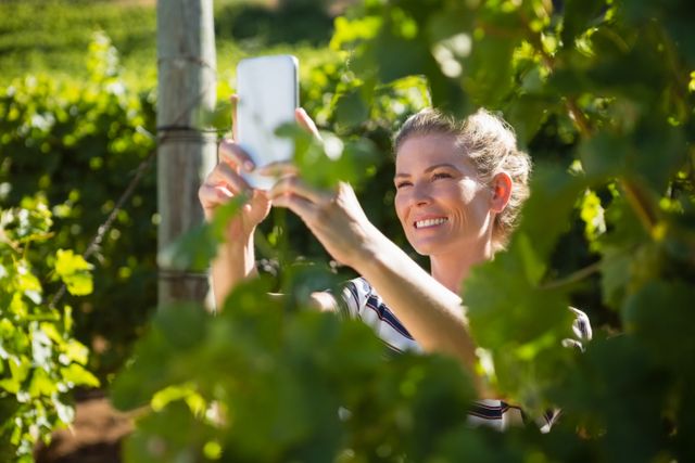 Happy woman talking selfie with mobile phone in vineyard on a sunny day
